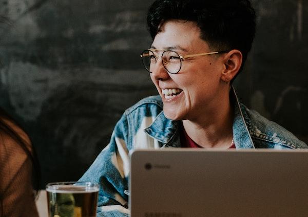 Person smiling, sitting next to laptop