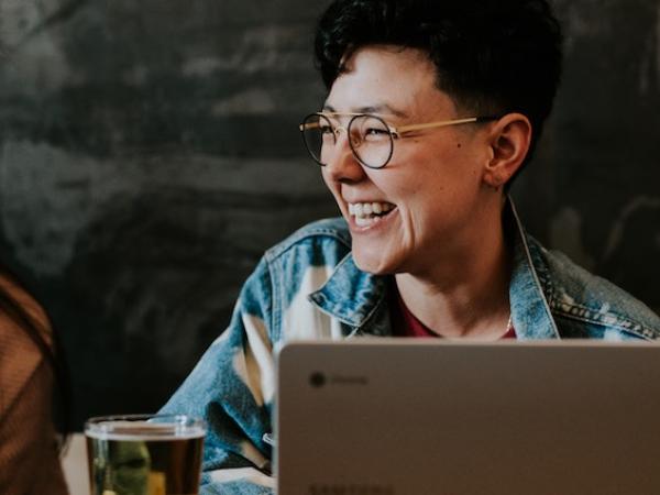 Person smiling, sitting next to laptop